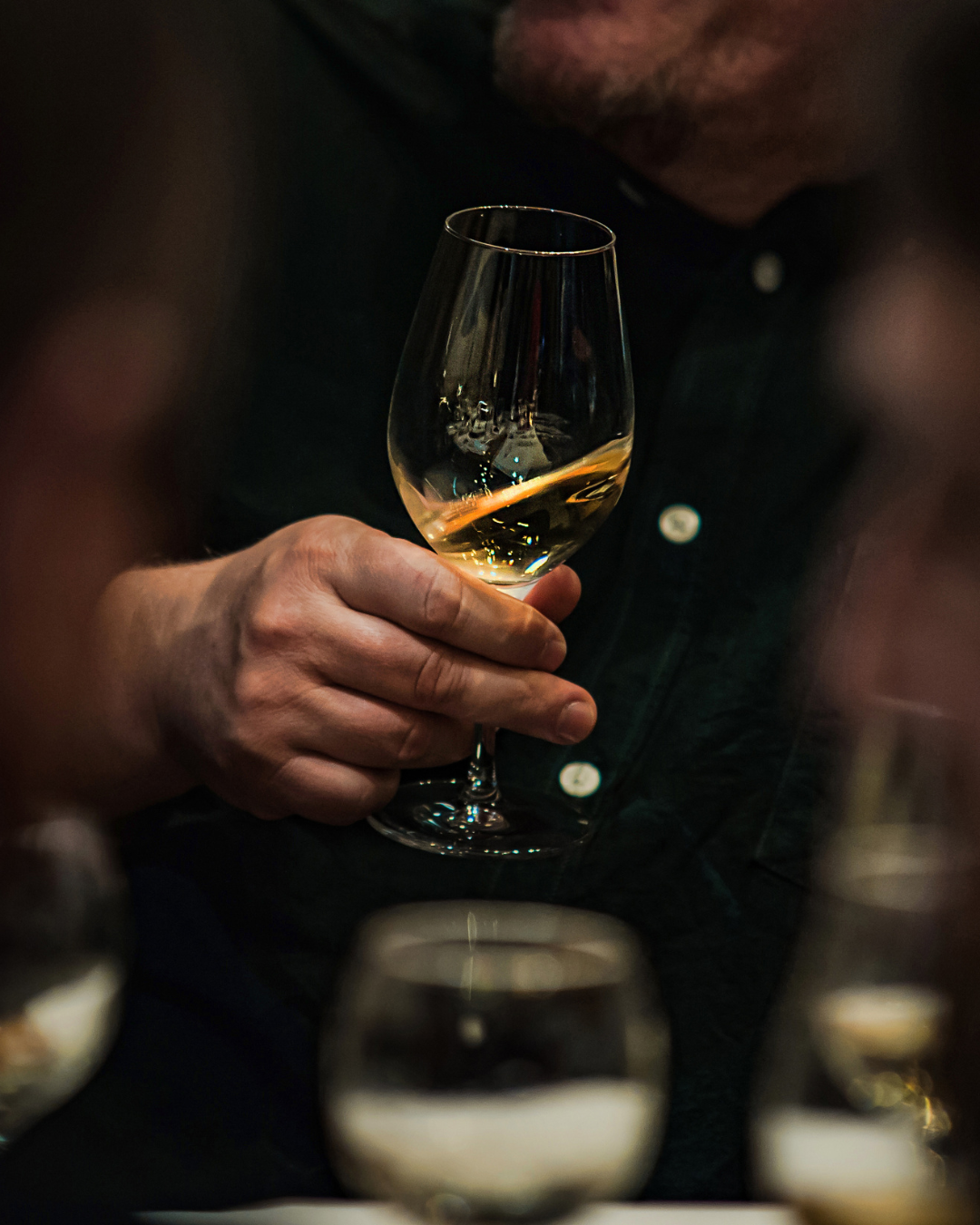 Calice di vino bianco tenuto in mano durante una degustazione